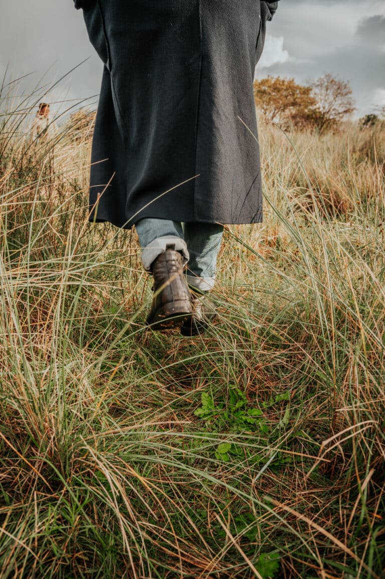 Close-up van iemand die loopt door de duinen door het helmgras