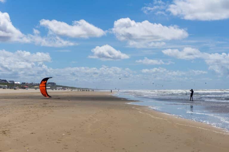 Kitesurfers op het strand van Zandvoort tijdens een winderige dag in juli aan de Noordzee.