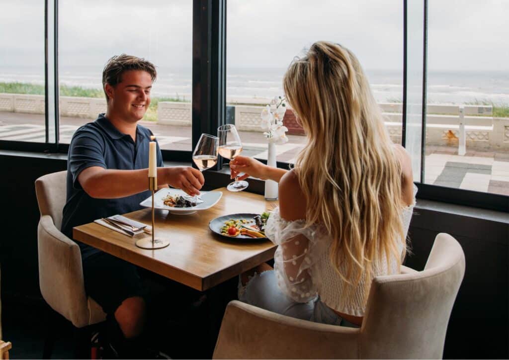 Gasten dineren en proosten met uitzicht op zee bij Zizo Lounge in Zandvoort.