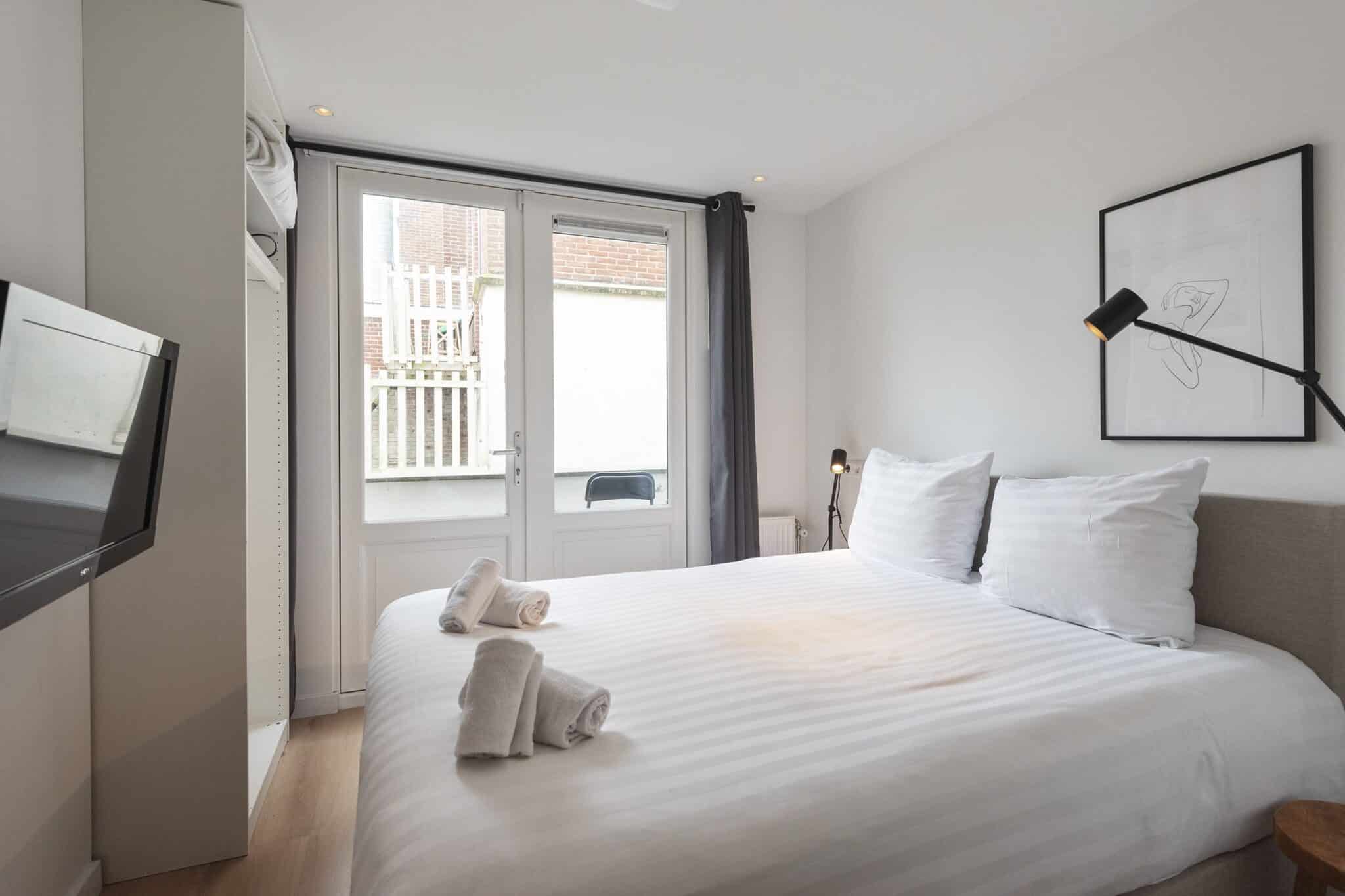 Bed met het balkon op de achtergrond van beach studio Zen in het centrum van Zandvoort