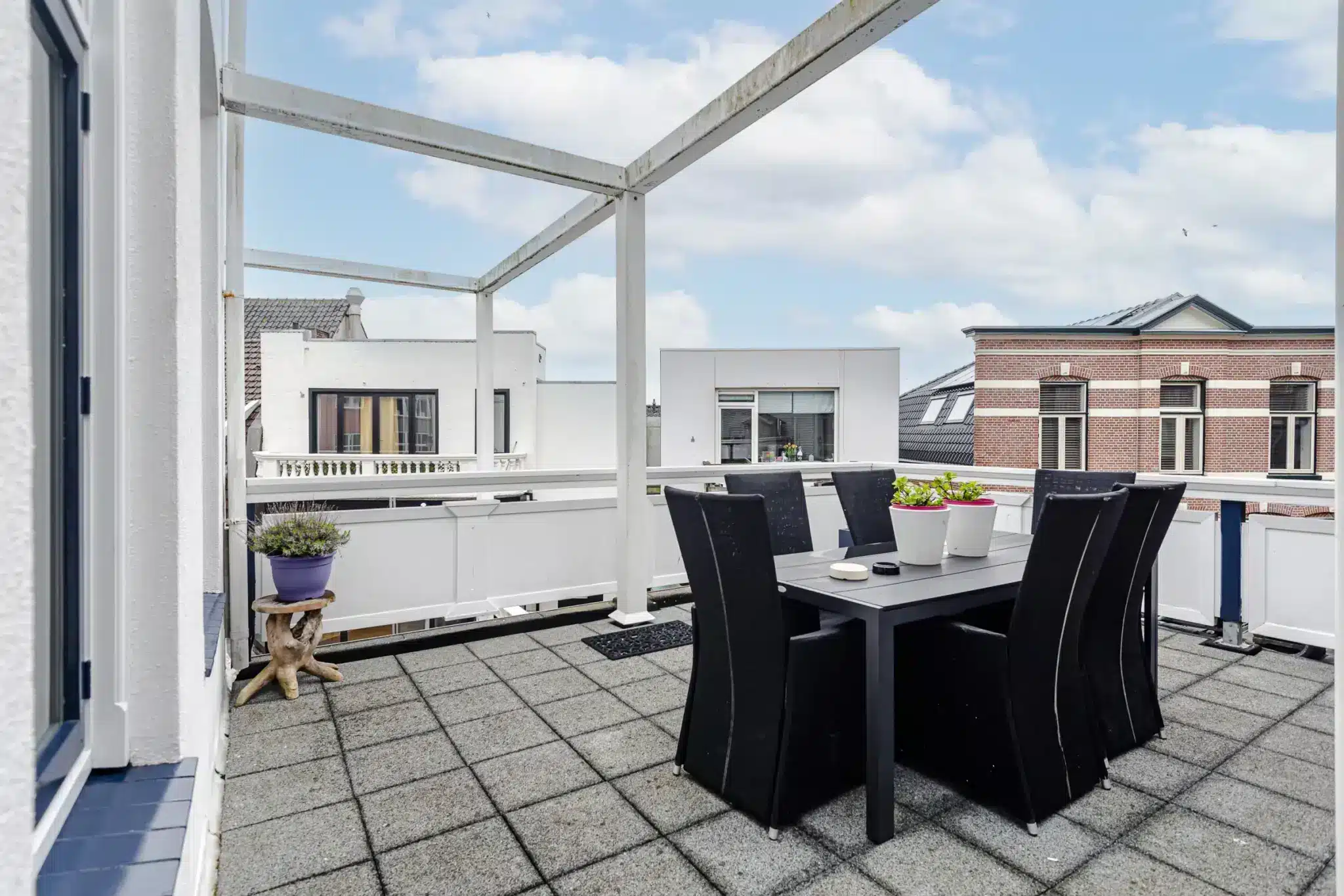 Modern dakterras van appartement Zandvoort Zenith met ruime eettafel, comfortabele stoelen en vrij uitzicht op de omliggende bebouwing.